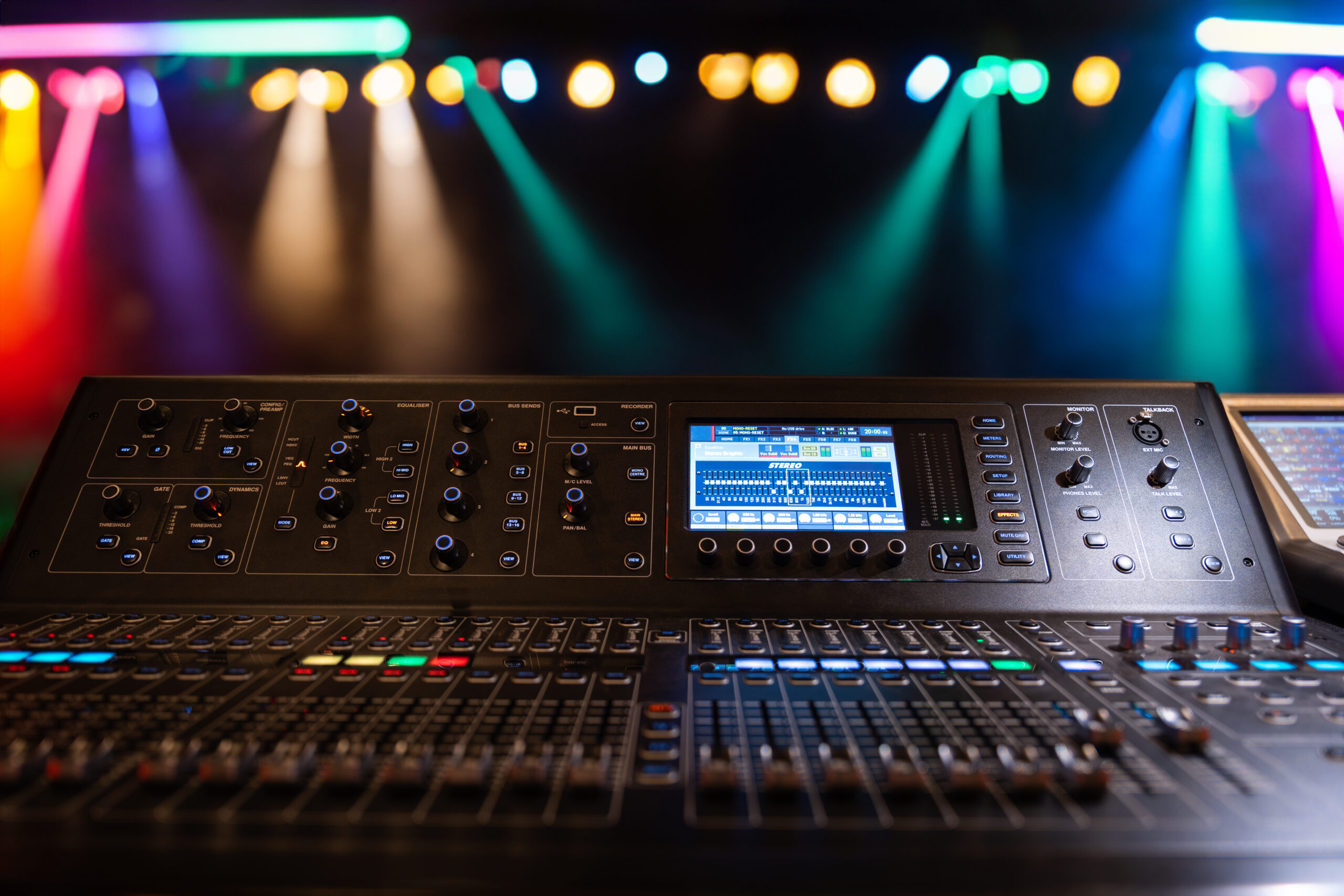 live theater concert show sound video music control console with scene lights background. sound engineer mixer soundboard equipment with many knobs, buttons, faders, equalizer screen and light